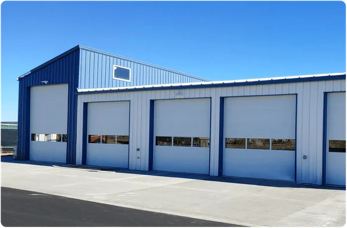 Blue and white metal garage building with several bay doors. Sunny day.